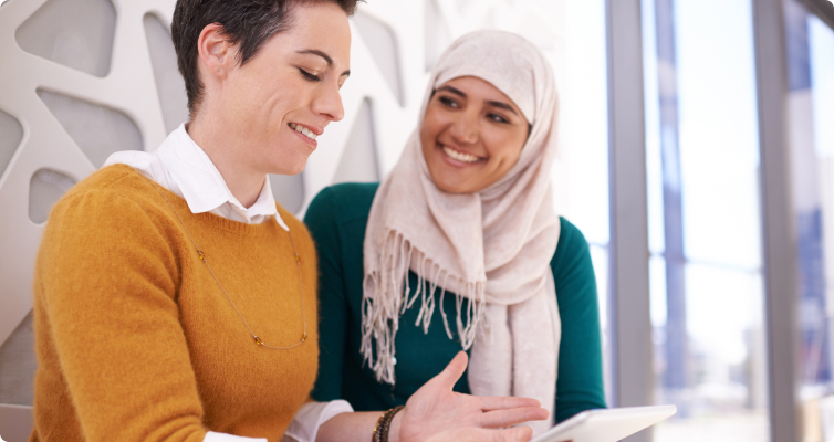 Two women have a discussion while standing in an office