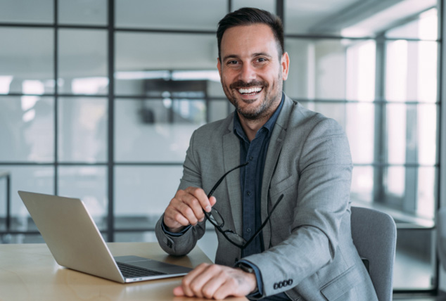 Man sits casually at corporate desk, looking at the camera
