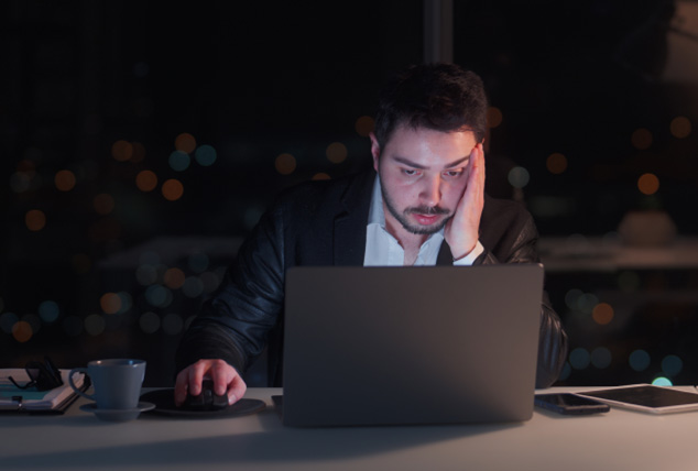 Woman works on her laptop at desk late at night