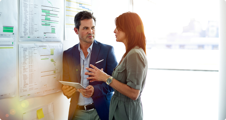 Two women have a discussion while standing in an office
