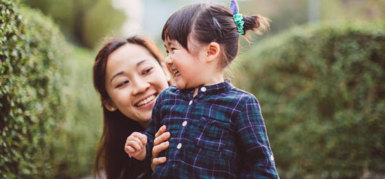 Asian mother with child smiling outdoors